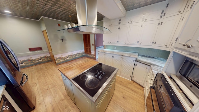 kitchen with light countertops, light wood finished floors, island range hood, and white cabinetry