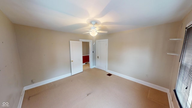 unfurnished bedroom featuring baseboards, visible vents, a ceiling fan, and light colored carpet