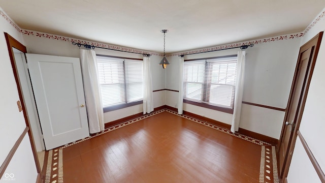 empty room featuring baseboards and dark wood finished floors