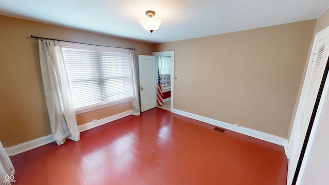 empty room featuring visible vents, baseboards, and wood finished floors