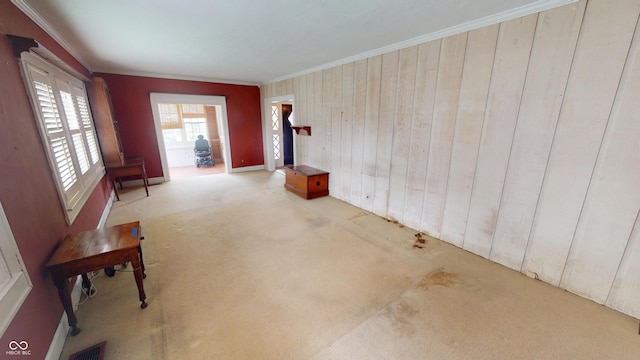 interior space featuring crown molding, wooden walls, visible vents, and carpet