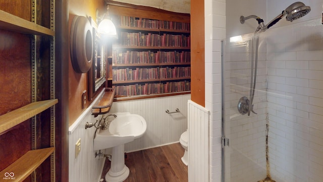 full bathroom featuring a stall shower, toilet, and wood finished floors
