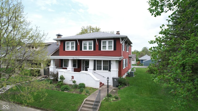 view of front of house with a front lawn, central AC, covered porch, and a chimney