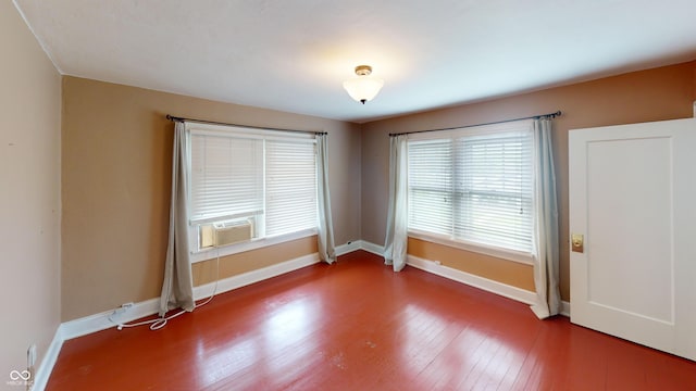 spare room featuring baseboards, wood finished floors, and cooling unit