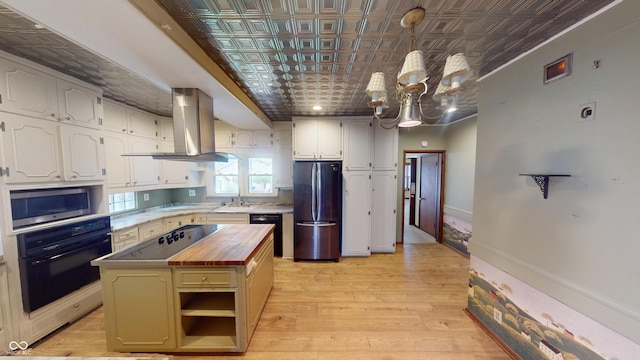 kitchen featuring an ornate ceiling, butcher block countertops, island exhaust hood, and black appliances