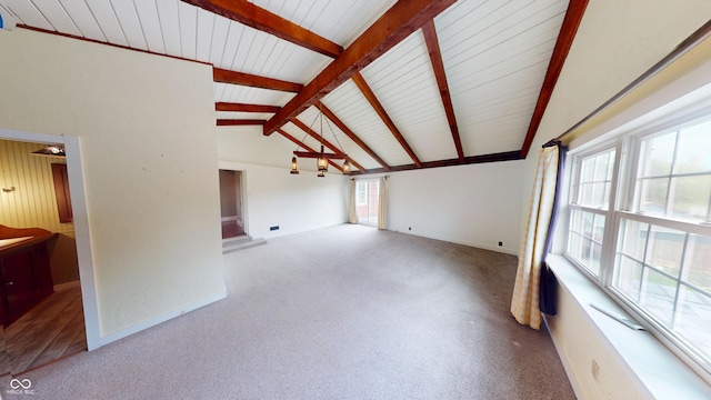 unfurnished living room featuring carpet floors, lofted ceiling with beams, and baseboards