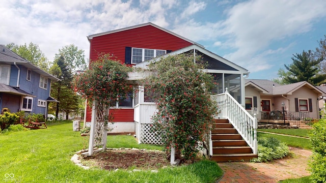 view of front of home featuring a sunroom, a front lawn, and stairway