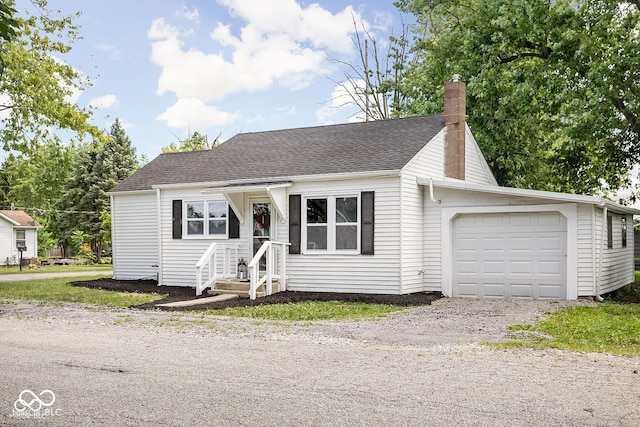 view of front of home featuring driveway, a chimney, roof with shingles, and a garage