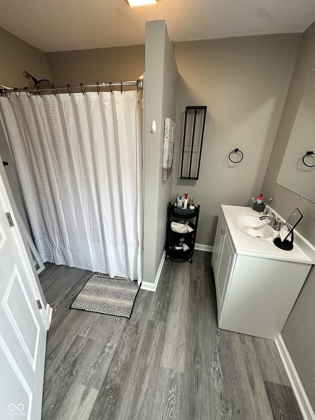 bathroom with vanity, baseboards, a shower with curtain, and wood finished floors