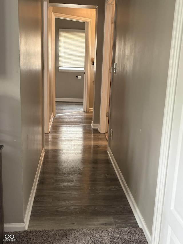 hall with baseboards and dark wood-style flooring