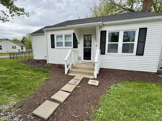 bungalow-style home with fence, a chimney, roof with shingles, and a front yard