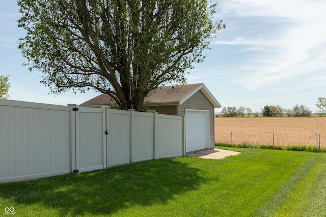 view of yard featuring fence, a gate, driveway, and a garage