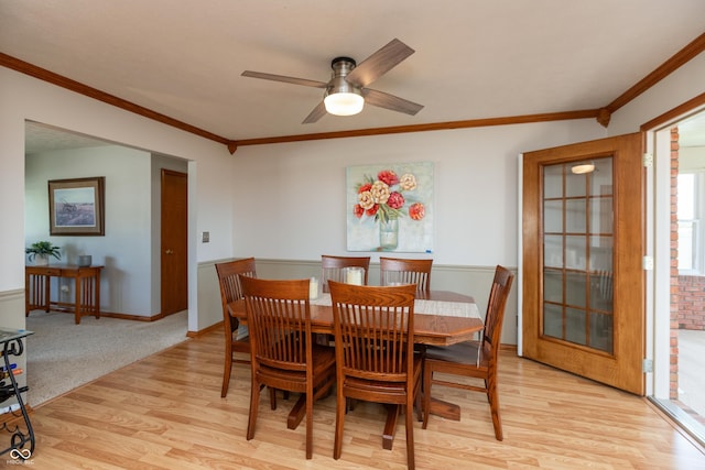 dining room with crown molding, a ceiling fan, baseboards, and light wood-type flooring