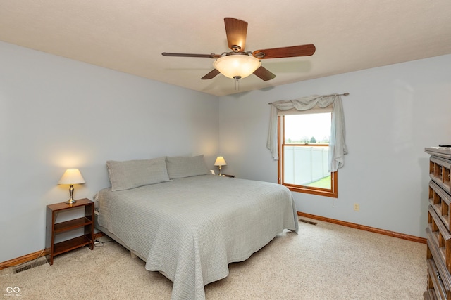 bedroom with baseboards, a fireplace, a ceiling fan, and light colored carpet