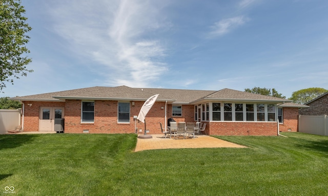 back of house with crawl space, a lawn, a patio area, brick siding, and fence