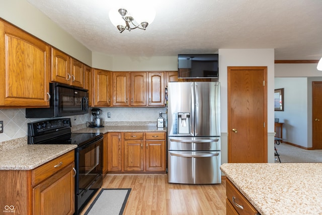 kitchen featuring decorative backsplash, black appliances, and brown cabinets