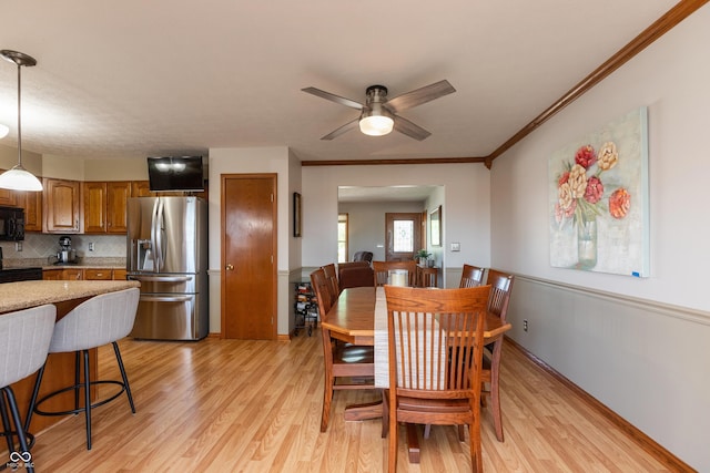dining room with ceiling fan, ornamental molding, and light wood-type flooring