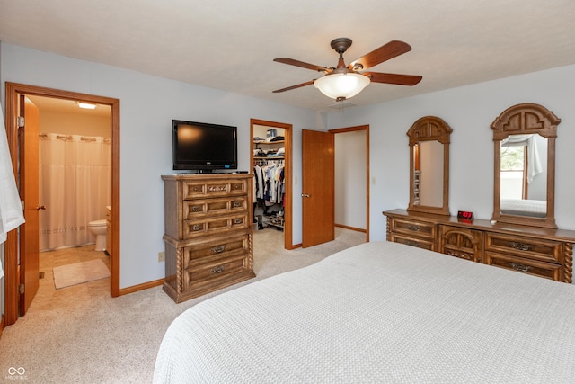 bedroom featuring a walk in closet, ensuite bathroom, a closet, and light colored carpet