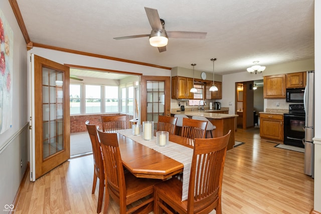 dining space with light wood-type flooring, ornamental molding, baseboards, and ceiling fan
