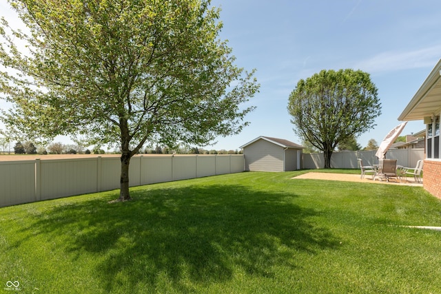 view of yard with a patio, a fenced backyard, and an outbuilding