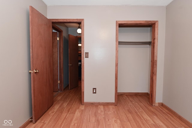 unfurnished bedroom featuring a closet, light wood finished floors, and baseboards