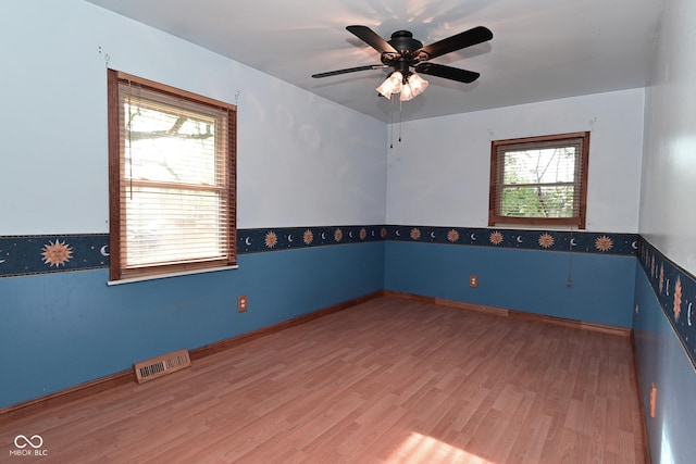 spare room with a ceiling fan, baseboards, visible vents, and wood finished floors