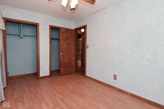 unfurnished bedroom with baseboards, multiple closets, ceiling fan, and wood finished floors