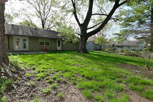 view of yard featuring fence and french doors
