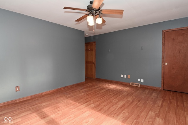 empty room with visible vents, a ceiling fan, light wood finished floors, and baseboards