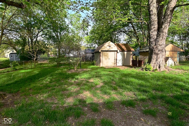 view of yard featuring fence, a storage unit, and an outbuilding