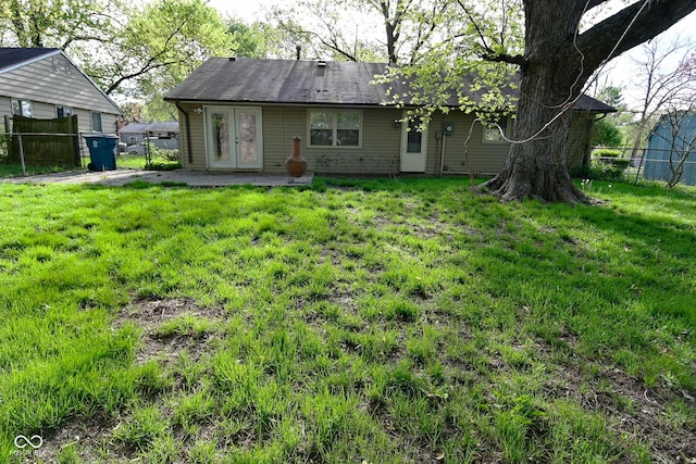 back of property featuring a lawn, fence, and french doors
