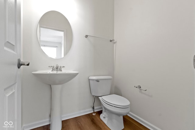 bathroom featuring baseboards, wood finished floors, and toilet