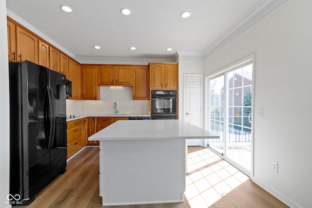 kitchen featuring decorative backsplash, a center island, light wood-type flooring, black refrigerator with ice dispenser, and ornamental molding