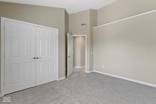 unfurnished bedroom with visible vents, baseboards, high vaulted ceiling, a closet, and carpet