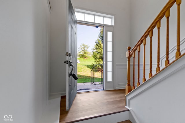 entrance foyer featuring stairs, a decorative wall, and wood finished floors