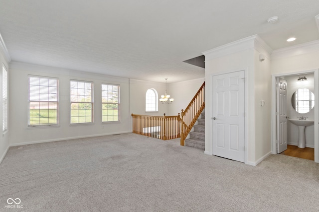 unfurnished living room featuring a sink, ornamental molding, carpet, and a notable chandelier