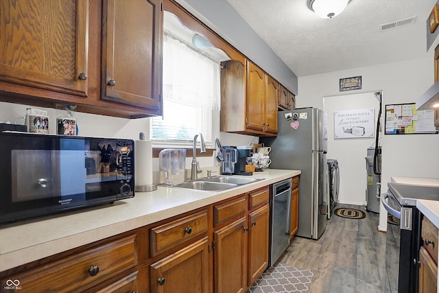 kitchen with range with electric stovetop, black microwave, stainless steel dishwasher, a sink, and light countertops