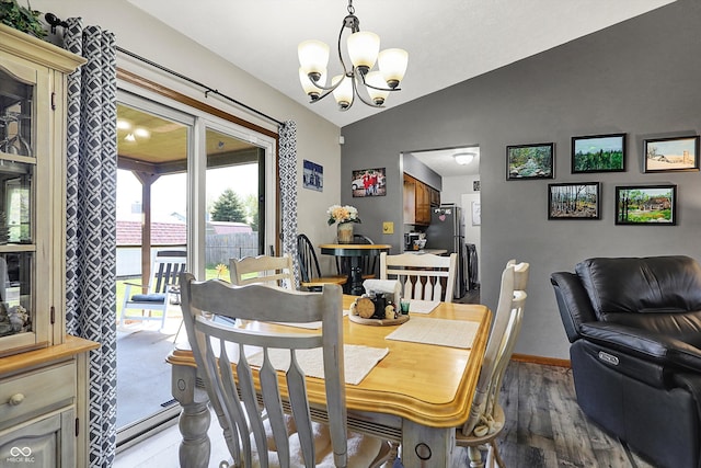 dining room with baseboards, a notable chandelier, wood finished floors, and lofted ceiling