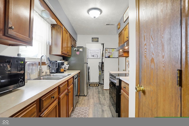 kitchen with light countertops, a sink, under cabinet range hood, and stainless steel appliances