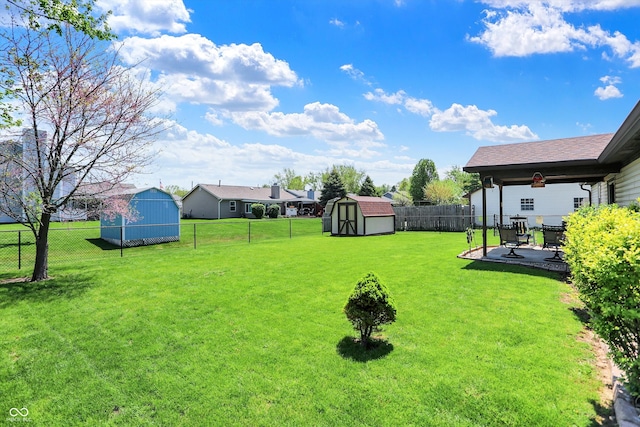 view of yard featuring an outbuilding, a fenced backyard, a patio area, and a storage unit