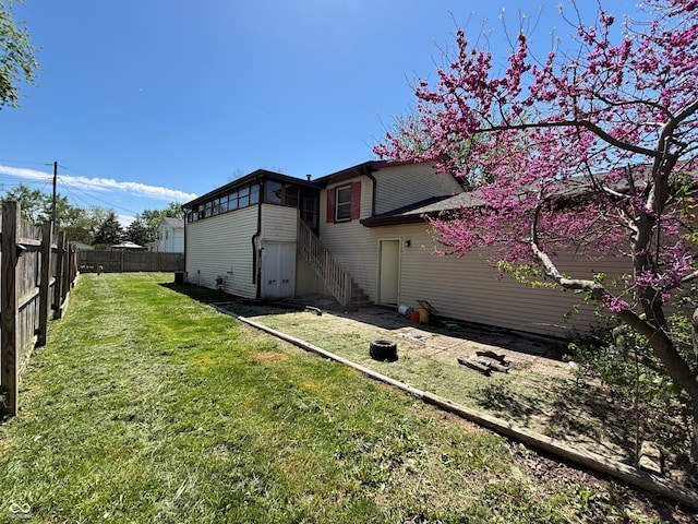 rear view of house featuring stairs, a lawn, and fence