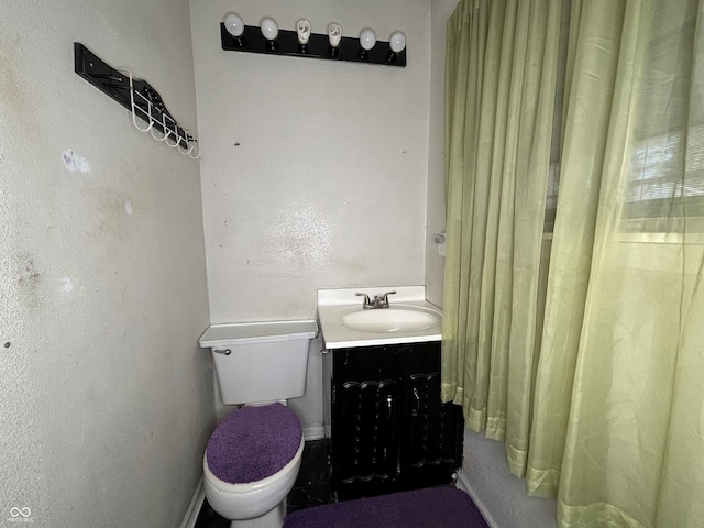 bathroom with toilet, baseboards, and vanity