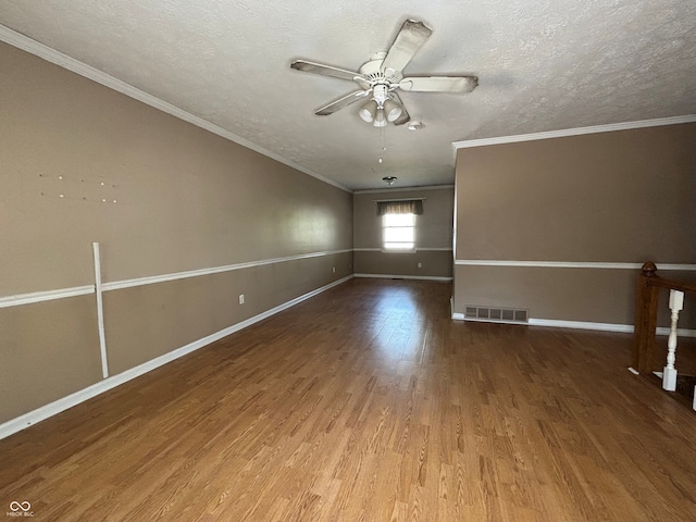 spare room with a textured ceiling, ceiling fan, wood finished floors, and visible vents