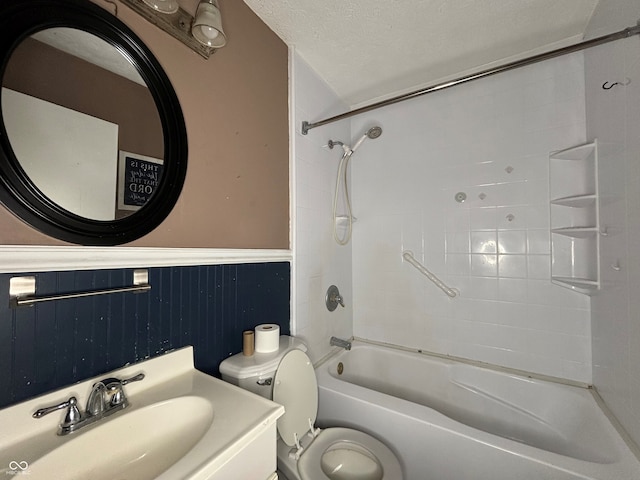 full bathroom with a textured ceiling, shower / tub combination, vanity, a wainscoted wall, and toilet