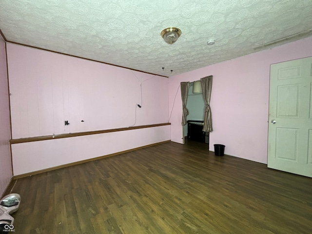 unfurnished room with dark wood-style flooring and a textured ceiling