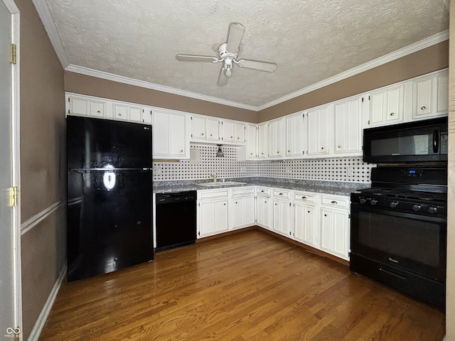 kitchen with dark countertops, a sink, white cabinets, black appliances, and dark wood-style floors