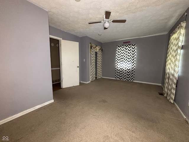 carpeted spare room with baseboards, a ceiling fan, and a textured ceiling
