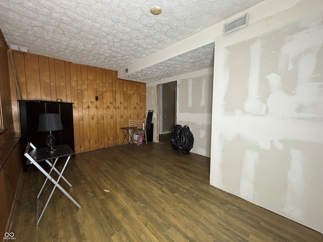 unfurnished living room featuring wooden walls, visible vents, and wood finished floors
