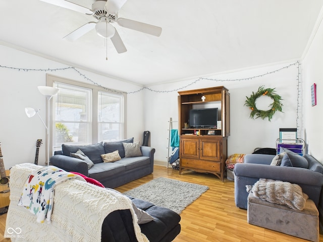 living room featuring ornamental molding, a ceiling fan, and light wood finished floors