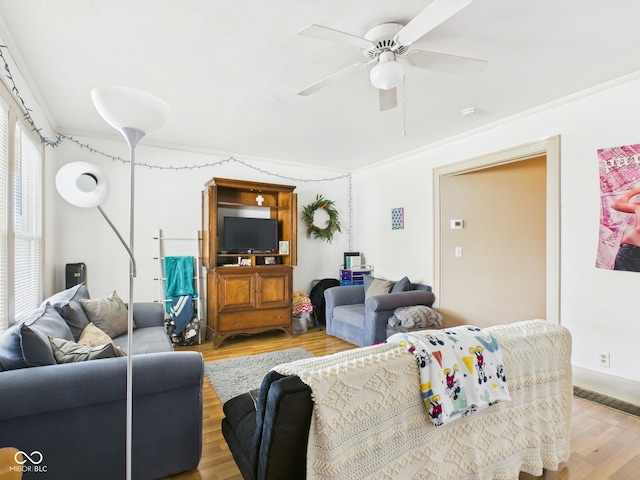 living area featuring crown molding, ceiling fan, and light wood-style flooring
